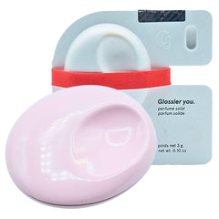 Perfume sólido Glossier You, compacto metálico rosa, uso diario.