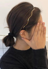 Diadema Huachi en dorado con diseño en onda, añade elegancia duradera a cualquier estilo.