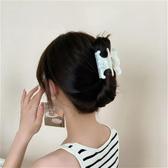 Clip acetato JITUIHOM diseño doble C en blanco marfil, sujetando peinados con delicadeza.