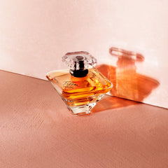 Lancôme Trésor frasco dorado con tapón de diamante, lujo visible.