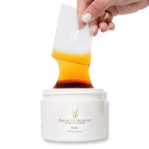 Sugar Me Smooth cera de azúcar derramándose desde la botella, depilación suave sin irritación.