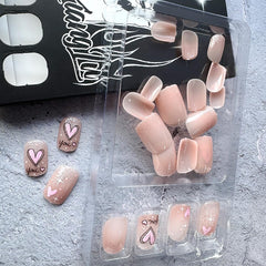 Uñas con corazones rosas en nude, look suave y romántico.