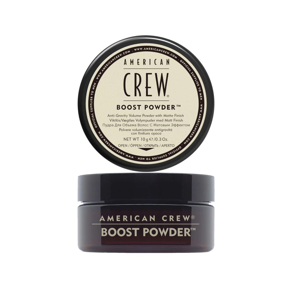 Polvo de impulso para cabello de American Crew en la mano, creando control y volumen ligero.