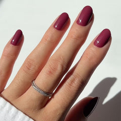 Uñas postizas Glamnetic en color granate morado oscuro para un acabado elegante.