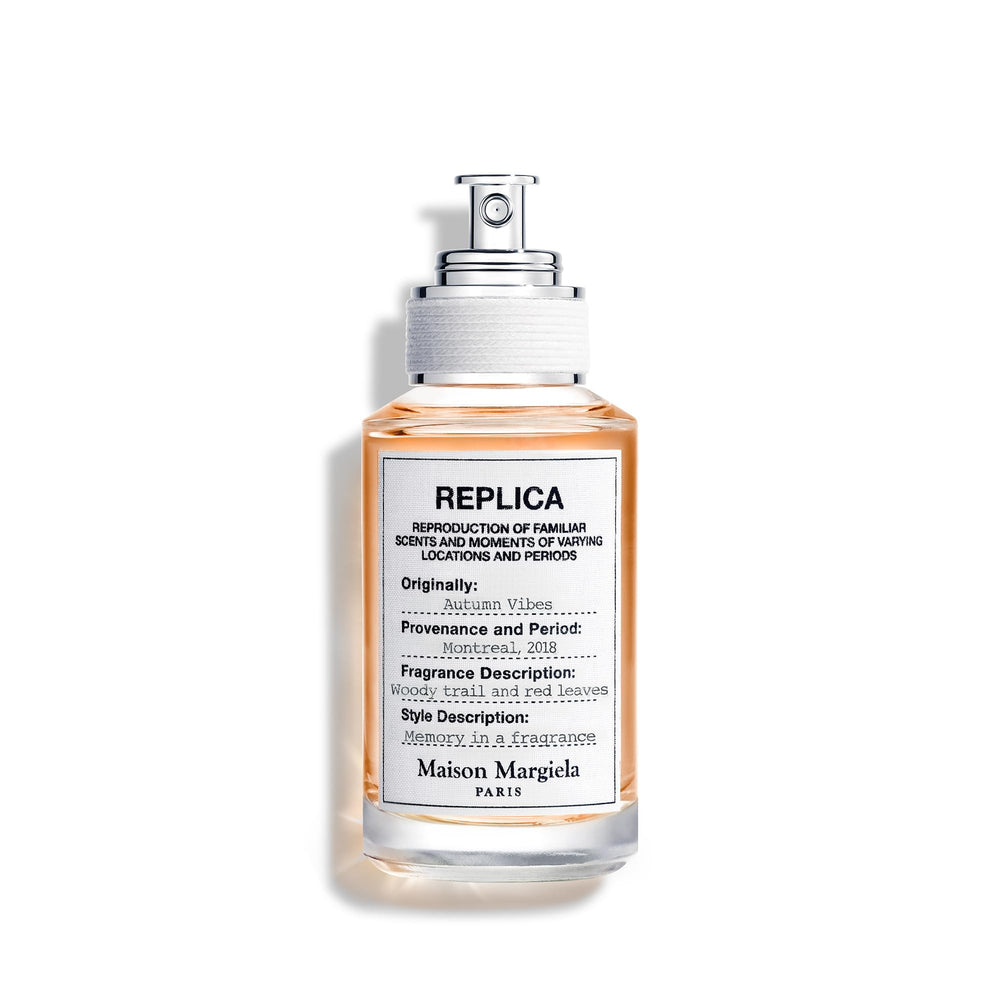Replica Vibras de Otoño: botella en entorno otoñal para aroma amaderado evocador.