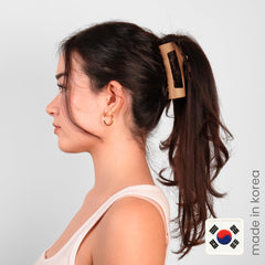 MELLO clip garra cabello café mediano en mano, color natural.