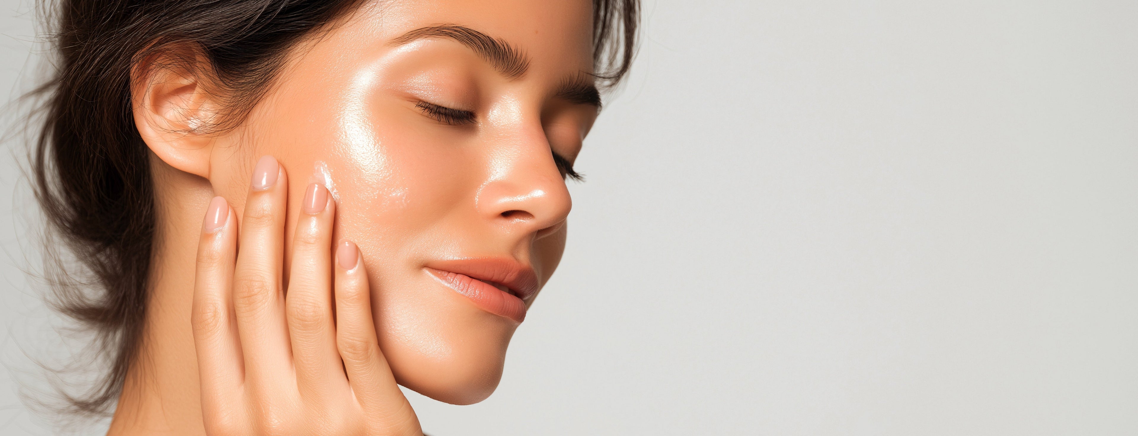Mujer con piel luminosa tocando su rostro como parte de una rutina de cuidado de la piel, sobre un fondo claro y minimalista con mensaje de belleza natural.