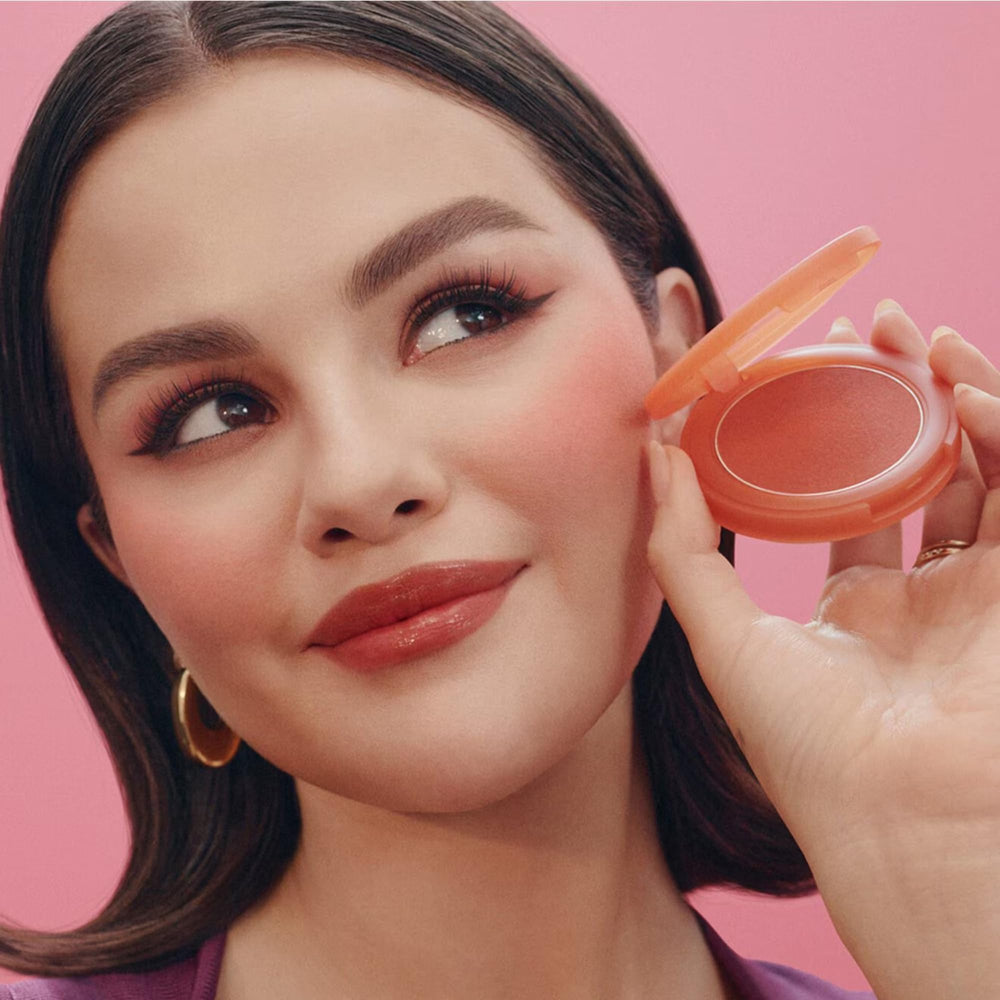 Mini blush liquide Worth de Rare Beauty, application fluide sur les joues.