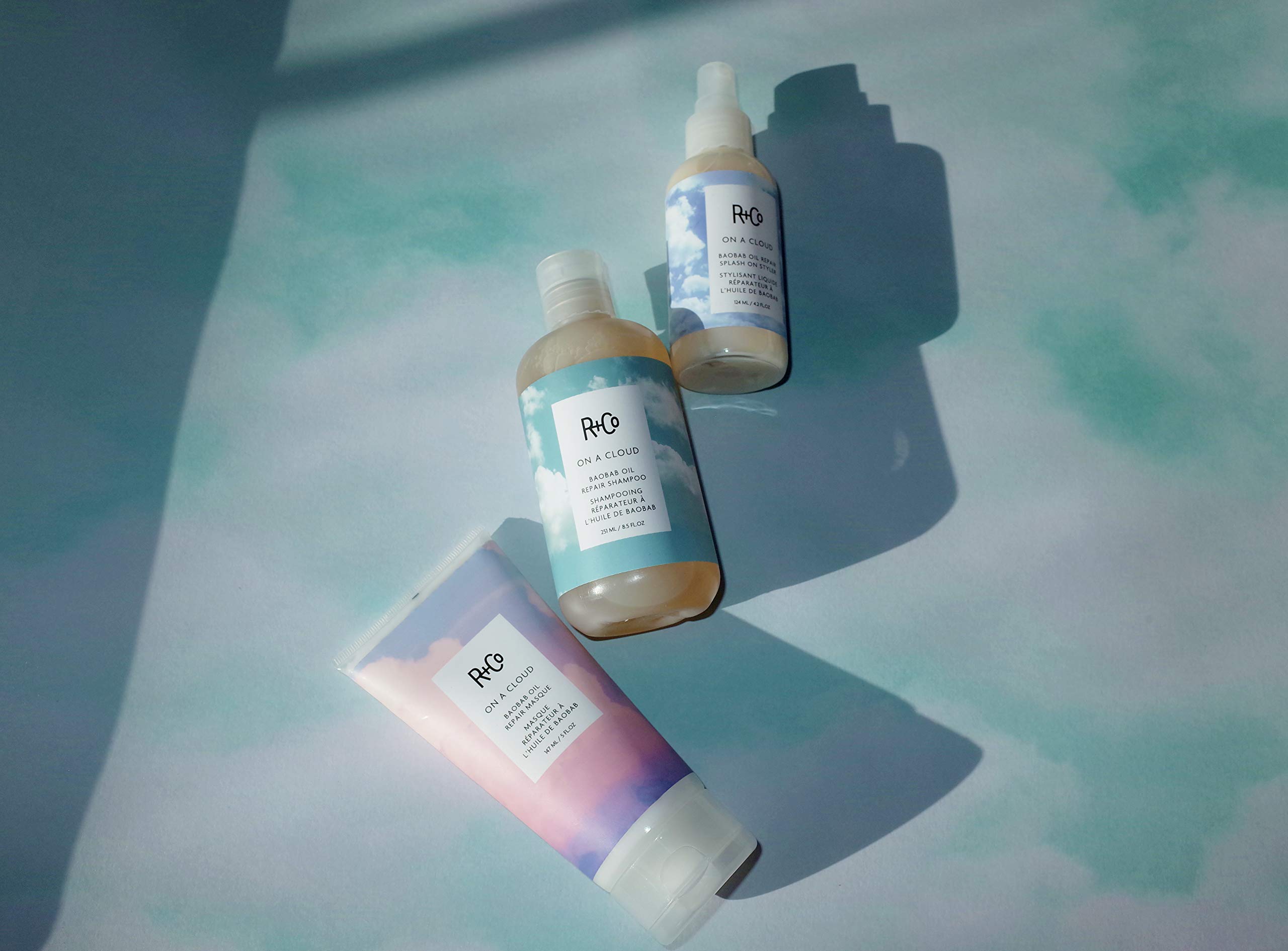 Envase de R+Co Baobab en baño minimalista para cuidado diario.