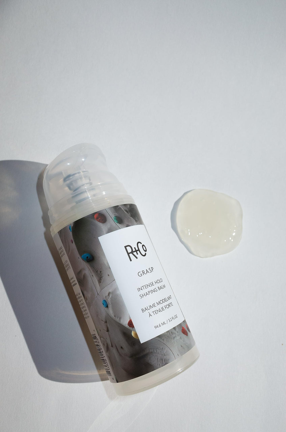 R+Co Grasp Balm en el bote, diseño compacto para uso diario.