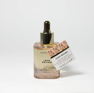 Sand + Fog Love Potion dropper application shown for easy, lasting fragrance