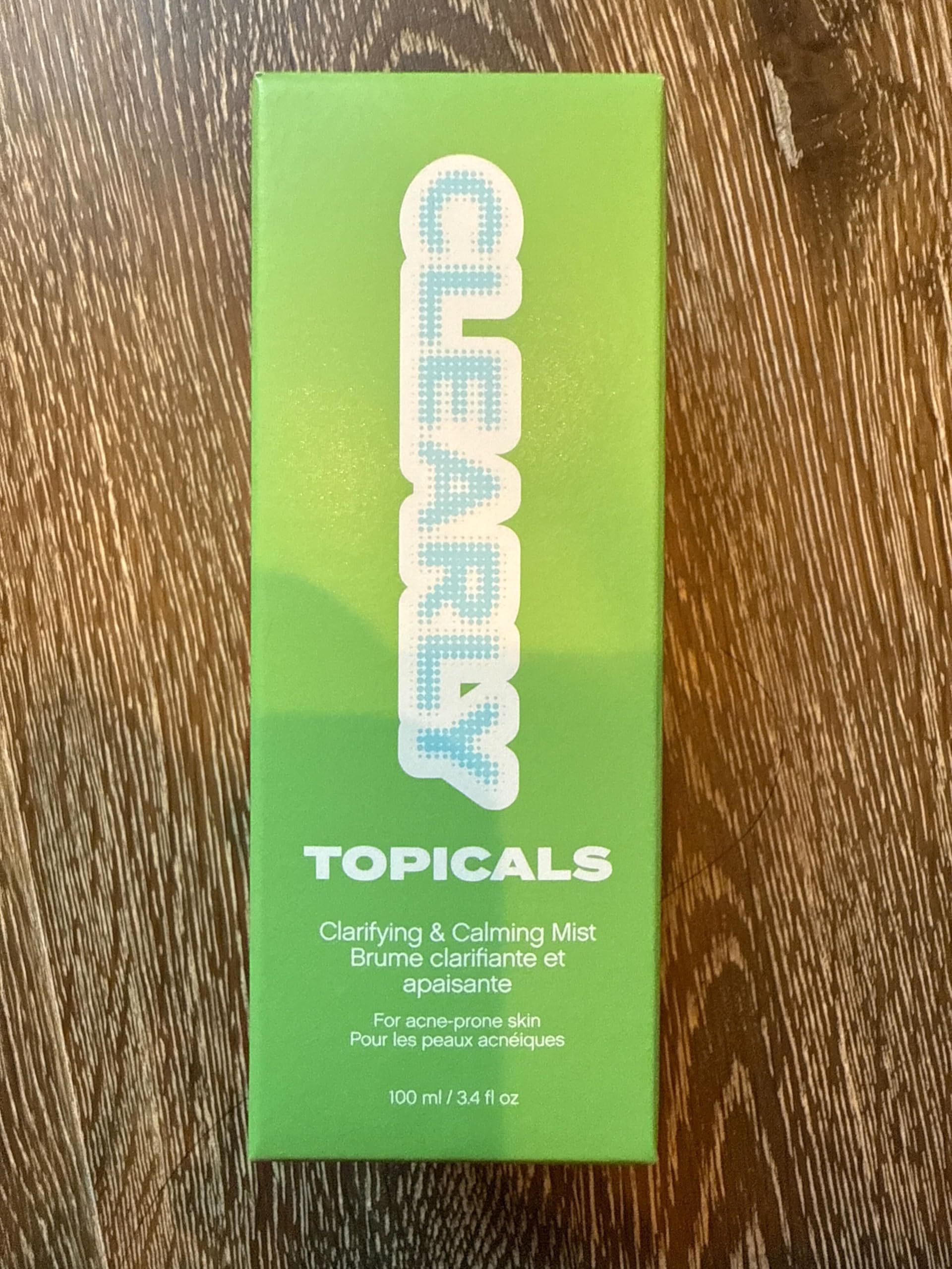 Topicals Clearly Acne brume — pulvérisateur en main, application facile sur la peau.